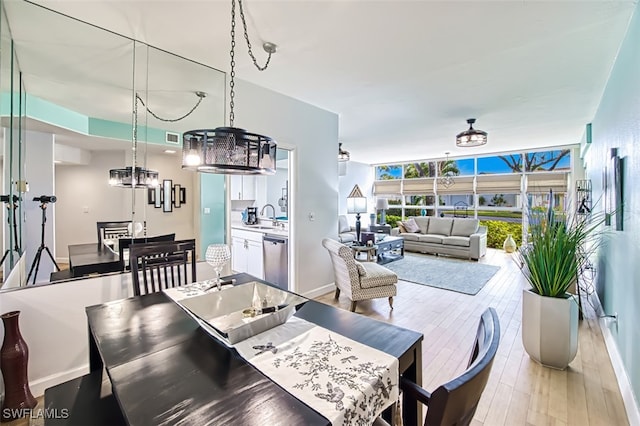 dining space with floor to ceiling windows, a notable chandelier, light hardwood / wood-style floors, and sink