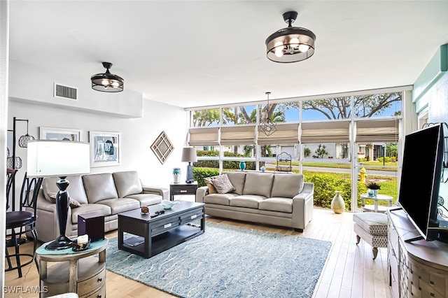 living room with light wood-type flooring, expansive windows, and a healthy amount of sunlight