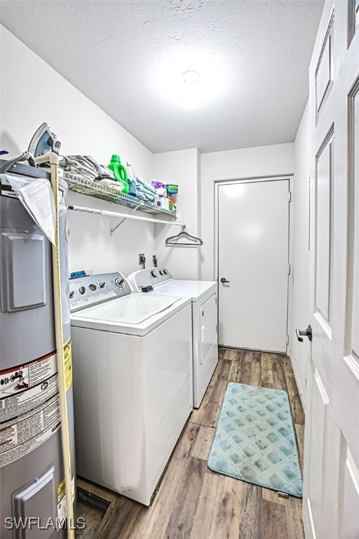 washroom featuring hardwood / wood-style flooring, washing machine and dryer, a textured ceiling, and water heater