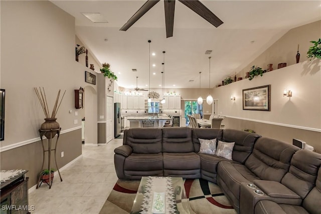 living room featuring ceiling fan, light tile patterned flooring, and lofted ceiling