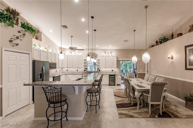 kitchen featuring light stone countertops, hanging light fixtures, beverage cooler, backsplash, and white cabinets