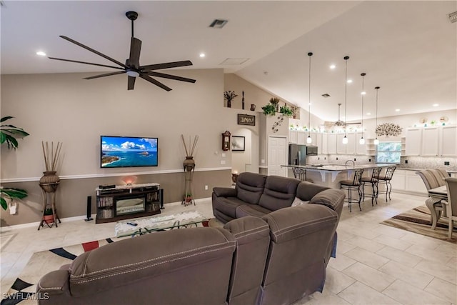 tiled living room with ceiling fan and high vaulted ceiling