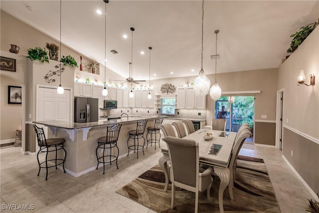 dining space with sink, high vaulted ceiling, ceiling fan, and light tile patterned flooring