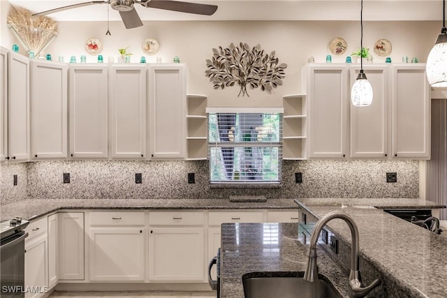 kitchen with white cabinets, decorative backsplash, decorative light fixtures, and dark stone counters