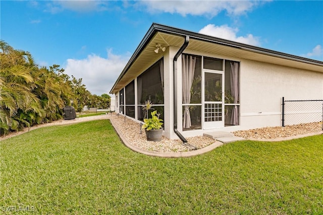 view of home's exterior with a sunroom and a yard