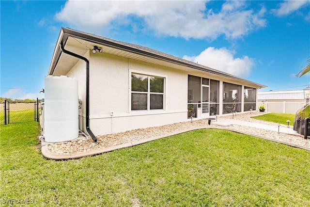 back of property with a sunroom and a lawn