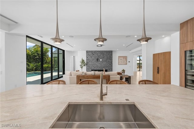 kitchen with a healthy amount of sunlight, pendant lighting, a sink, and light stone countertops