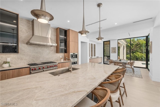 kitchen featuring a sink, tasteful backsplash, modern cabinets, and wall chimney exhaust hood