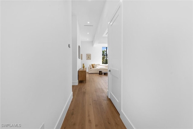hall featuring hardwood / wood-style flooring, baseboards, and recessed lighting