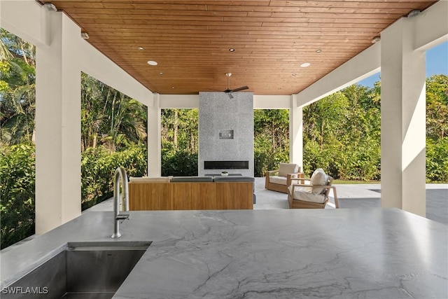 view of patio / terrace with a sink, an outdoor living space with a fireplace, and exterior kitchen