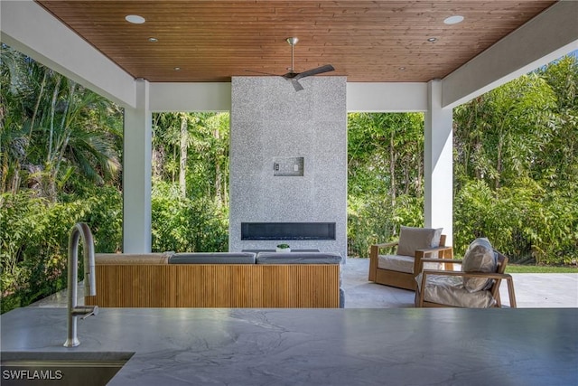 view of patio / terrace featuring exterior fireplace, ceiling fan, and a sink