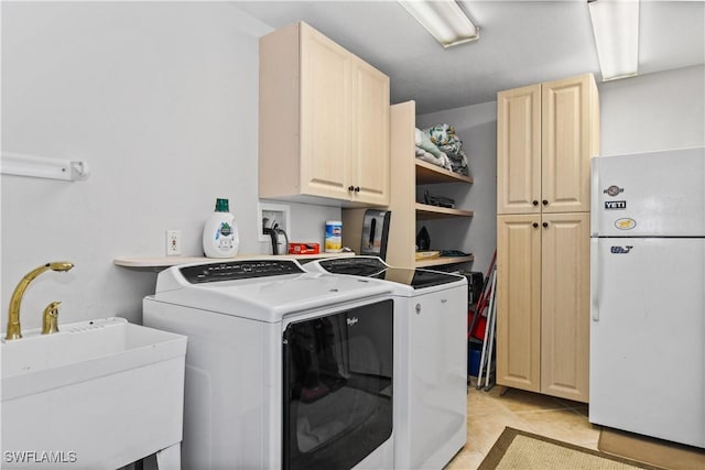 washroom with cabinets, light tile patterned floors, washing machine and dryer, and sink