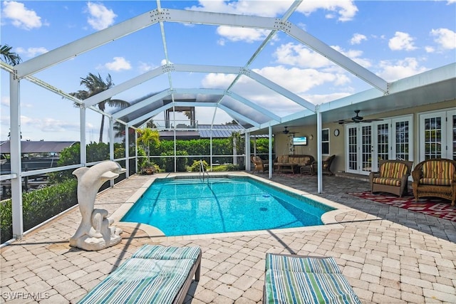 view of pool featuring glass enclosure, a patio area, french doors, and ceiling fan