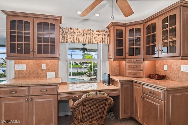 kitchen featuring decorative backsplash, light tile patterned floors, and built in desk