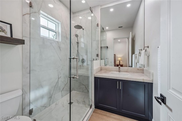 bathroom featuring a shower with door, vanity, wood-type flooring, and toilet