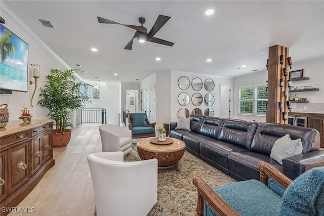 living room featuring ceiling fan, light wood-type flooring, and crown molding