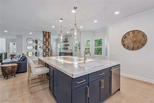 kitchen with light stone counters, sink, pendant lighting, dishwasher, and an island with sink