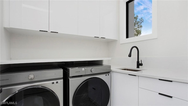 laundry room with sink, washing machine and clothes dryer, and cabinets