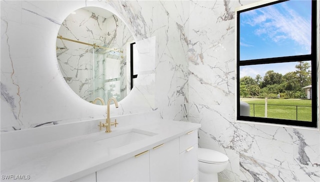 bathroom with vanity, toilet, a wealth of natural light, and tile walls