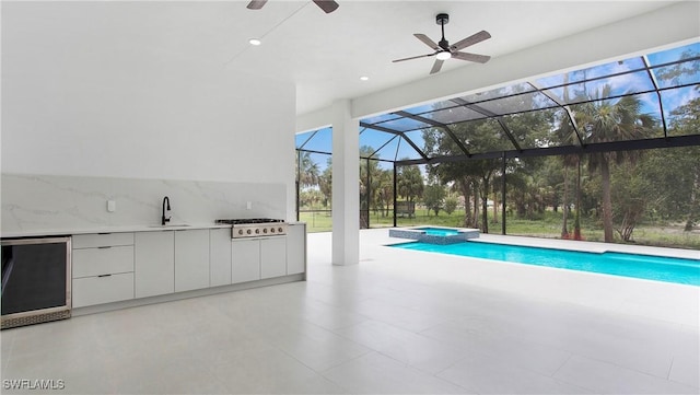 view of swimming pool with an in ground hot tub, a patio area, an outdoor kitchen, sink, and a lanai