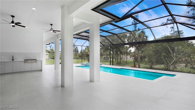 view of pool featuring exterior kitchen, glass enclosure, ceiling fan, and a patio