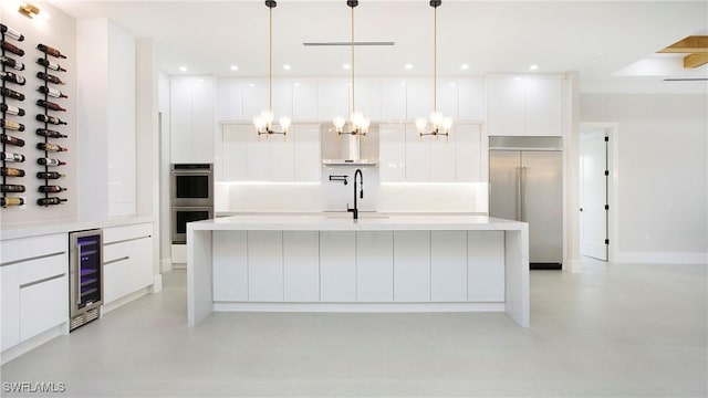 kitchen with pendant lighting, white cabinetry, stainless steel appliances, sink, and a kitchen island with sink