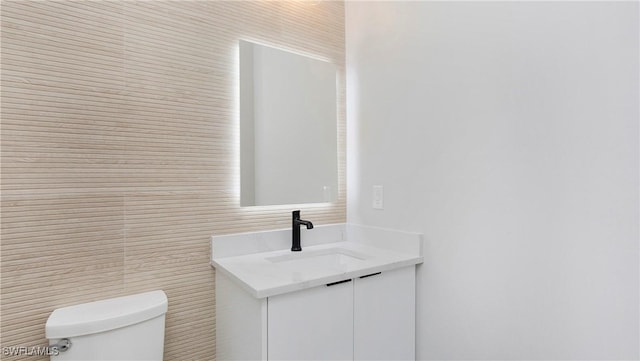 bathroom with toilet, tile walls, and vanity