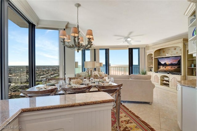 tiled dining area featuring ceiling fan with notable chandelier, plenty of natural light, crown molding, and expansive windows