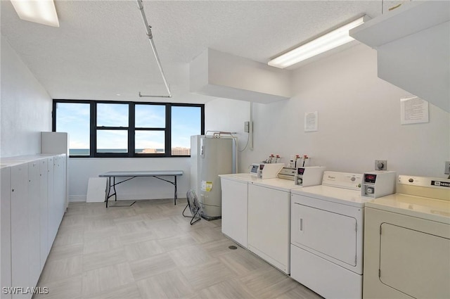 laundry room with washing machine and clothes dryer, water heater, and a textured ceiling