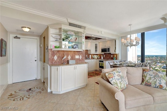 living room featuring a chandelier, light tile patterned floors, and crown molding