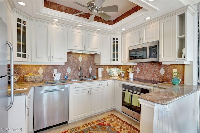 kitchen with kitchen peninsula, white cabinets, appliances with stainless steel finishes, and sink