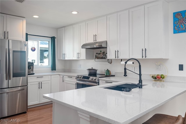 kitchen with white cabinetry, sink, stainless steel appliances, a kitchen breakfast bar, and kitchen peninsula