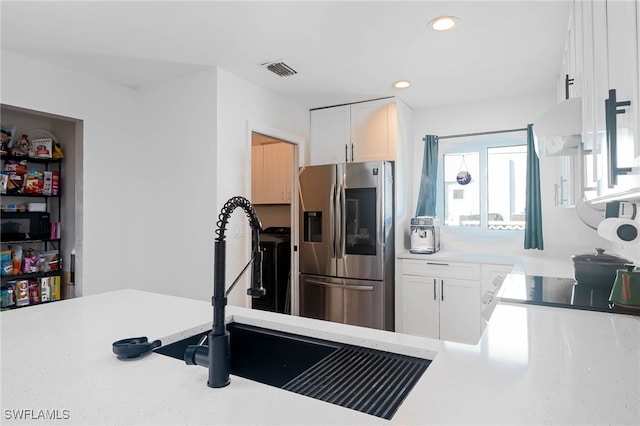 kitchen featuring stainless steel fridge, white cabinetry, and sink