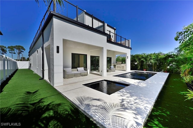 back of property with a balcony, a patio area, a fenced in pool, and an outdoor kitchen