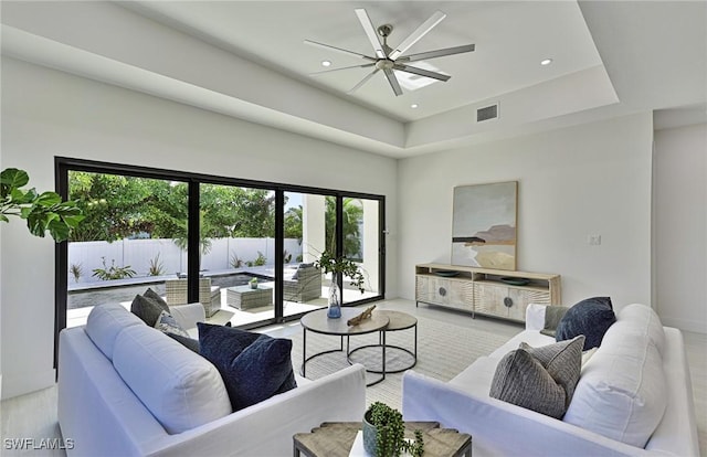 living room with ceiling fan and a tray ceiling