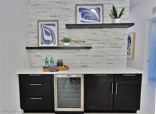 bar with beverage cooler, tasteful backsplash, and light stone countertops