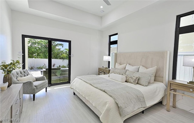 bedroom with ceiling fan, access to outside, and a raised ceiling