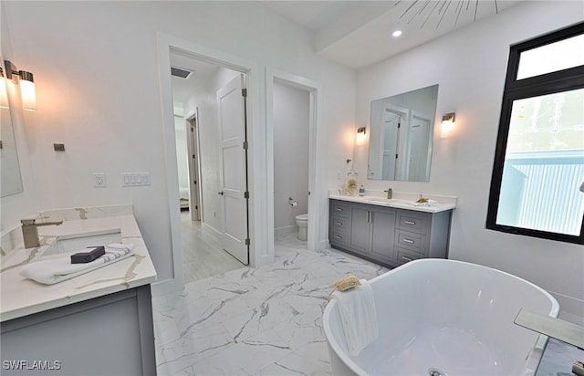 bathroom featuring a tub to relax in, vanity, toilet, and a healthy amount of sunlight