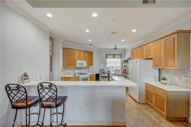 kitchen with white appliances, crown molding, light brown cabinetry, tasteful backsplash, and a breakfast bar area