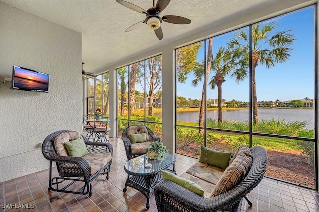 sunroom with ceiling fan and a water view