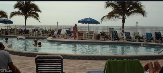 view of swimming pool featuring a water view and a patio area