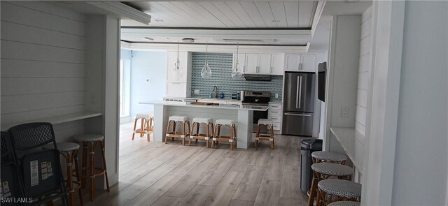 kitchen with white cabinets, wood ceiling, stainless steel appliances, a kitchen breakfast bar, and light wood-type flooring