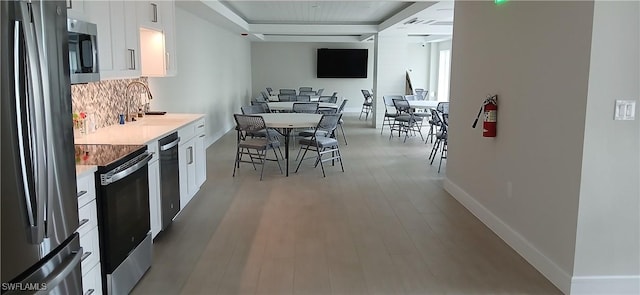 kitchen with appliances with stainless steel finishes, light hardwood / wood-style floors, white cabinets, and sink