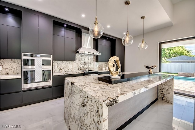 kitchen with pendant lighting, backsplash, a large island, stainless steel appliances, and wall chimney range hood