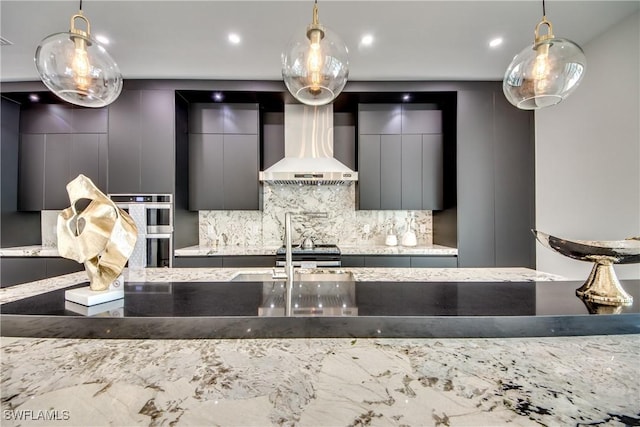 kitchen with stainless steel appliances, decorative light fixtures, wall chimney range hood, and decorative backsplash