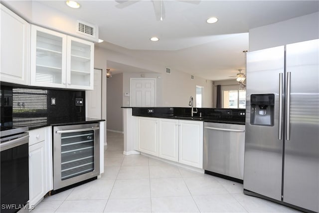 kitchen with decorative backsplash, stainless steel appliances, beverage cooler, sink, and white cabinetry