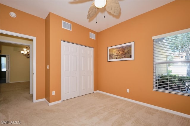 unfurnished bedroom featuring light carpet, a closet, and ceiling fan with notable chandelier