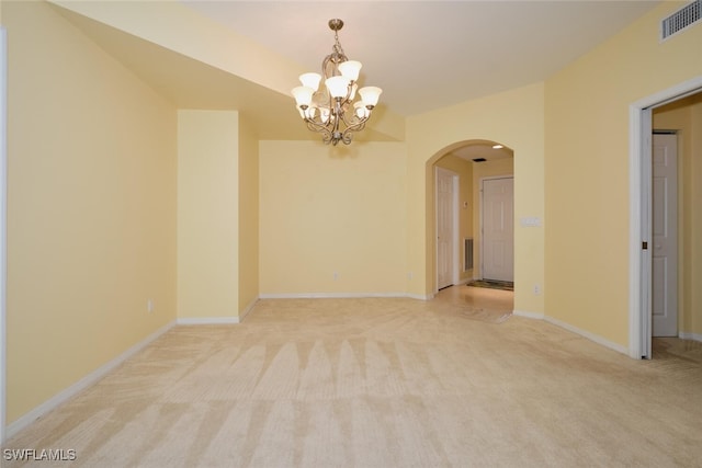 carpeted spare room featuring an inviting chandelier