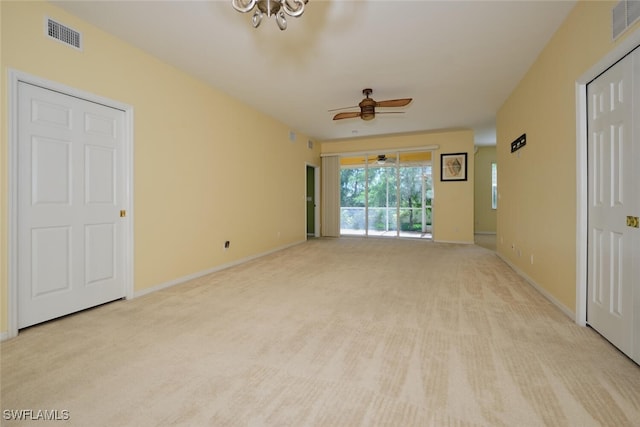 carpeted empty room with ceiling fan with notable chandelier