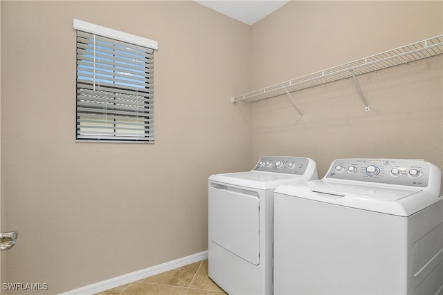 laundry area with washing machine and clothes dryer, laundry area, baseboards, and light tile patterned floors